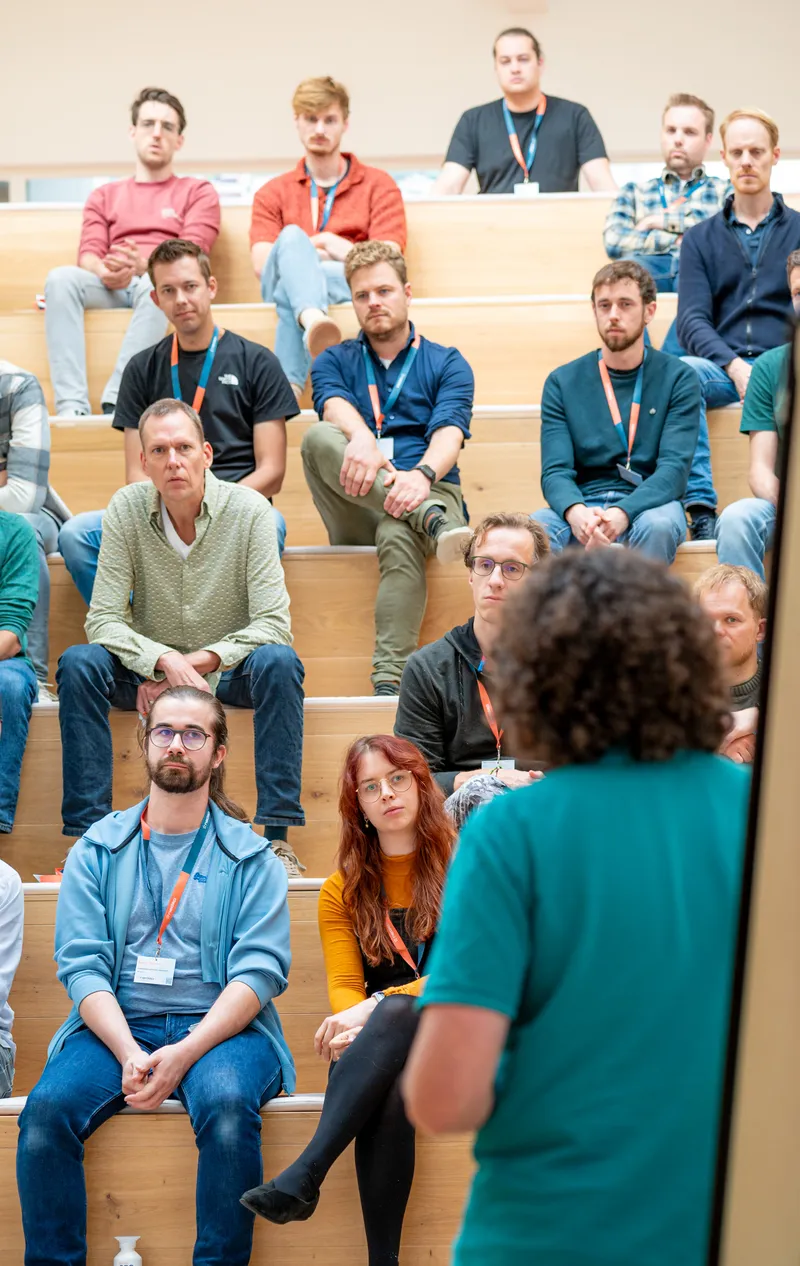 Engaged listeners sitting on stairs in a presentation room with a speaker in front of them