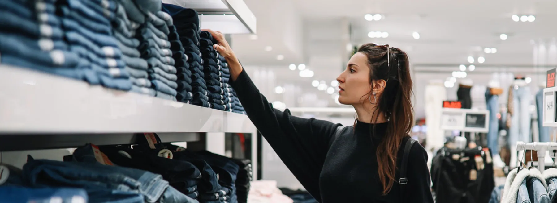 Shopper selecting jeans from shelves in an apparel store