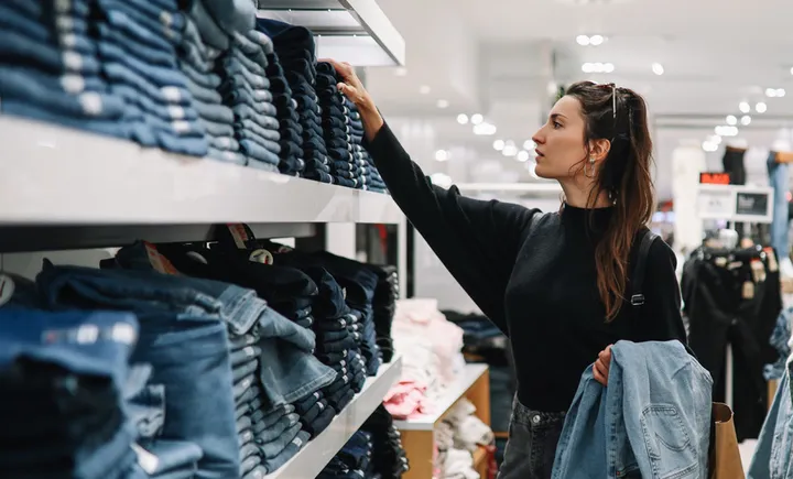 Shopper selecting jeans from shelves in an apparel store
